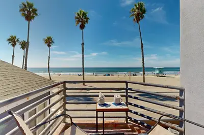 a table on the balcony of a beach with palm trees at The Strand Oasis in Oceanside