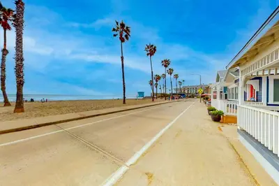 an empty street next to a beach with palm trees at The Strand Oasis in Oceanside