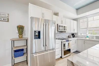 a kitchen with white cabinets and a stainless steel refrigerator at Ingraham Delight Pacific Beach in San Diego