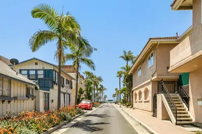 a street with palm trees and a red car at Rise and Shine in Newport Beach