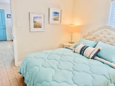 a bedroom with a bed with a blue comforter at Cozy Beach Cottage with Bicycles in San Diego