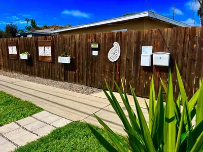 a fence with potted plants and signs on it at Cozy Beach Cottage with Bicycles in San Diego