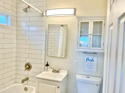 a bathroom with a sink and a toilet and a mirror at Cozy Beach Cottage with Bicycles in San Diego