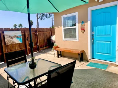 a patio with a table with a blue door and a bench at Cozy Beach Cottage with Bicycles in San Diego