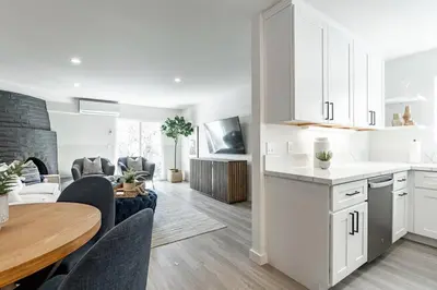 a kitchen and living room with white cabinets and a table at The Rosemont - La Jolla Luxury in San Diego