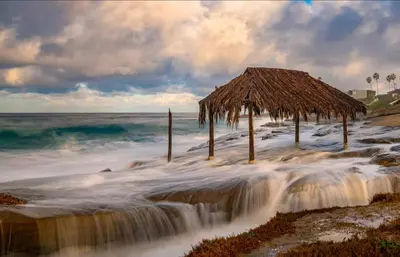 a beach with a straw hut and a waterfall at The Rosemont II - La Jolla Luxury in San Diego