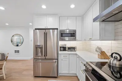a kitchen with white cabinets and a stainless steel refrigerator at Hideaway Zen in San Diego