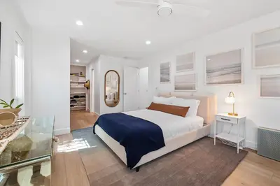 a white bedroom with a bed and a mirror at Hideaway Zen in San Diego