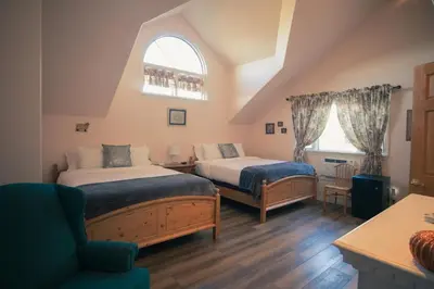 a bedroom with two beds and a chair and a window at Tucker Peak Lodge in Julian