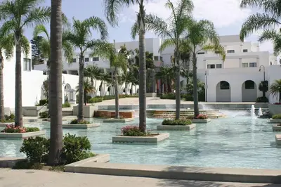 a pool with palm trees in front of a building at Mile to Beach! Fully Fenced Private SoCal Cottage in Oceanside
