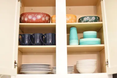 a cupboard filled with plates and bowls at Mile to Beach! Fully Fenced Private SoCal Cottage in Oceanside