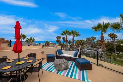 a patio with a table and chairs and the ocean at Buccaneer Beach Lookout - 30-Night Minimum in Oceanside
