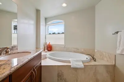 a bathroom with a tub and a sink and a window at Buccaneer Beach Lookout - 30-Night Minimum in Oceanside