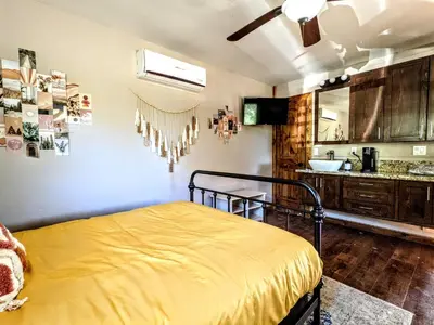 a bedroom with a yellow bed and a kitchen at The Bluebird's Nest - Cabin with Fireplace in Santa Ysabel