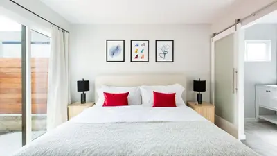 a bedroom with a white bed with red pillows at Hamilton II by AvantStay Beach House Rooftop Deck Newly Renovated Bungalow in San Diego