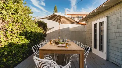 a wooden table and chairs on a patio with an umbrella at Topaz By AvantStay Adorable Cottage Walking Distance to Beach w Large Patio in San Diego