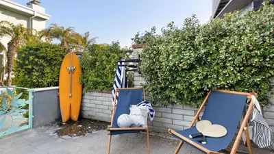 two chairs and a surfboard next to a wall at Mission Point 1 by AvantStay San Diego Beach House w Huge Patio Fire Pit Walk to Beach in San Diego
