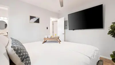 a white bedroom with a flat screen tv on the wall at Mission Point 1 by AvantStay San Diego Beach House w Huge Patio Fire Pit Walk to Beach in San Diego