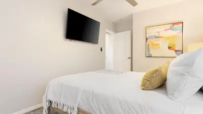 a bedroom with a white bed with a flat screen tv on the wall at Mission Point 1 by AvantStay San Diego Beach House w Huge Patio Fire Pit Walk to Beach in San Diego