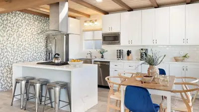 a kitchen with white cabinets and a table with chairs at Mission Point 2 by AvantStay Mission Beach Home w Large Balcony Steps to Beach in San Diego