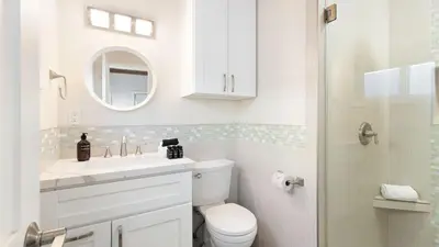 a white bathroom with a toilet and a mirror at Mission Point 2 by AvantStay Mission Beach Home w Large Balcony Steps to Beach in San Diego