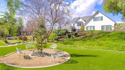 a garden with chairs and a tree in front of a house at The Riesling Retreat by AvantStay Estate w Pool HotTub Putting Green Pickle Ball Court in Sage