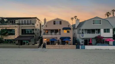 a group of buildings with blue umbrellas on a beach at Bay View II by AvantStay Ocean View Mission Beach Home on the Sand in San Diego