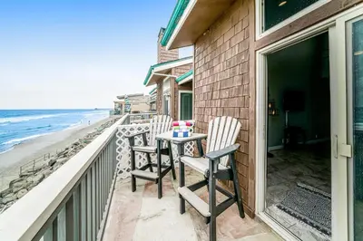 a balcony with two chairs and a table on the beach at Whitewater Village Charm in Oceanside