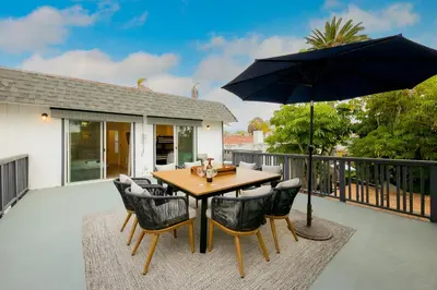 a wooden table with chairs and an umbrella on a patio at La Jolla Beach Retreat in San Diego