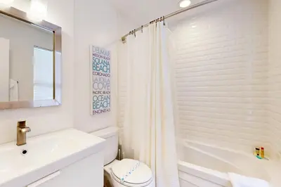 a white bathroom with a toilet and a sink at La Jolla Beach Retreat in San Diego