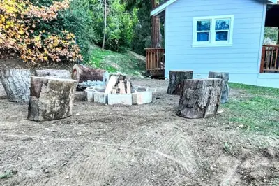 a yard with logs and a fire place with a house at The Luminous Lodge-Remodeled Cabin W/ Valley Views in Santa Ysabel