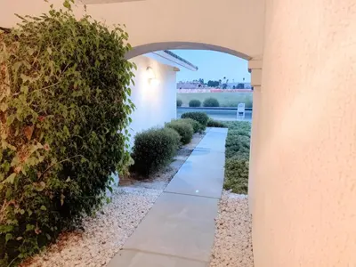 a walkway through a building with a hedge at Silver Sands Den in Hemet