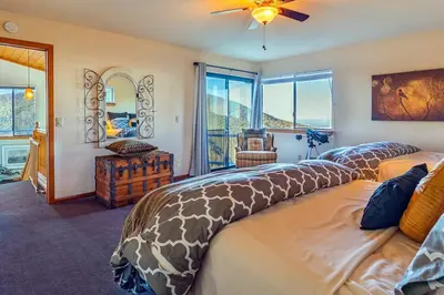 a bedroom with a large bed with a large window at A LIVING CANVAS Amazing Lake View Custom Home in Julian