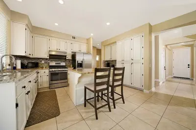 a kitchen with white cabinets and two chairs in it at Pool-BBQ-View-Balcony-Fireplace-King-Garage-WD in Lake Elsinore