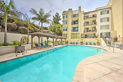 a swimming pool in front of a building at Breezy Oceanside Condo Less Than half Mi to Beach! in Oceanside