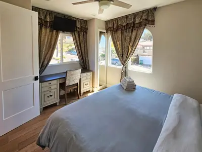 a bedroom with a bed and a desk and two windows at Modern comfort, prime location, 360 views, 4 BR entire house in San Diego