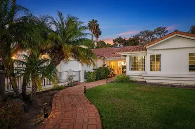 a white house with a palm tree and a brick driveway at Mi Casa es Su Casa! (My Home is Your Home!) in Vista
