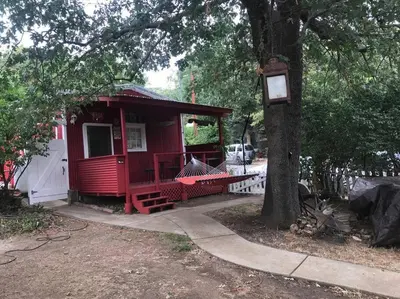 a red house sitting next to a tree at Cozy, Cheerful & Charming Cabin - Historic Julian in Julian