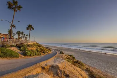 a road leading to a beach with palm trees and the ocean at Luxury Ocean Views & Steps To The Sand - Tower 36 Upper Condo Unit in Carlsbad