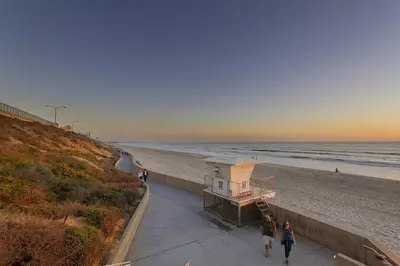 two people walking down a sidewalk next to the beach at Walk to Beach, AC, Firepit, Grill in Carlsbad