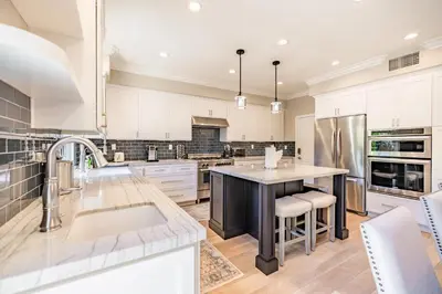 a kitchen with white cabinets and a large island at @ Marbella Lane - Modern and Sophisticated Home in Irvine