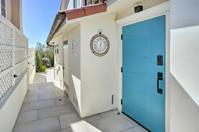 a clock on a wall next to a blue door at Luxe Laguna Home with Ocean View Walk to Beach in Laguna Beach