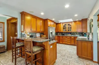 a kitchen with wooden cabinets and a island with bar stools at Oceanview, Walk To Beach, Fire Pit in Carlsbad