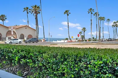 a beach with palm trees and a building and a street at Sunrise by the Sea 1 Block from Ocean in Oceanside