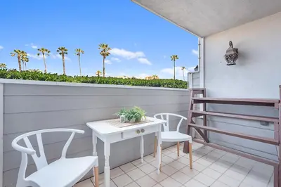 a balcony with a table and chairs and palm trees at Sunrise by the Sea 1 Block from Ocean in Oceanside