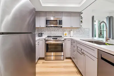 a kitchen with white cabinets and a stainless steel refrigerator at Life on the Point in San Diego