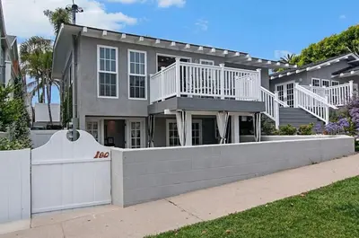 a large house with a white fence in front of it at Remodeled Beach Bungalow, Block to the Beach in Carlsbad
