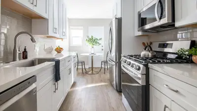 a kitchen with white cabinets and a stainless steel refrigerator at Seashore Suites by AvantStay in San Diego
