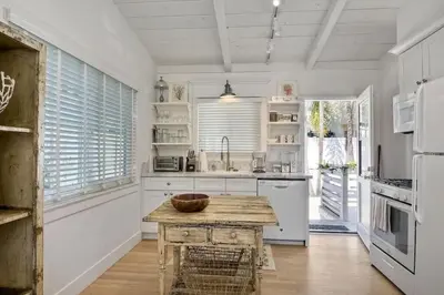 a kitchen with white cabinets and a wooden table at Walk to Beach, Patio with Ocean View, AC in Carlsbad