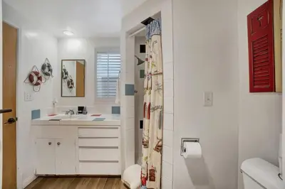 a white bathroom with a sink and a shower at ON THE SAND!! Private Beach! OCEAN FRONT HOT TUB!! in Dana Point